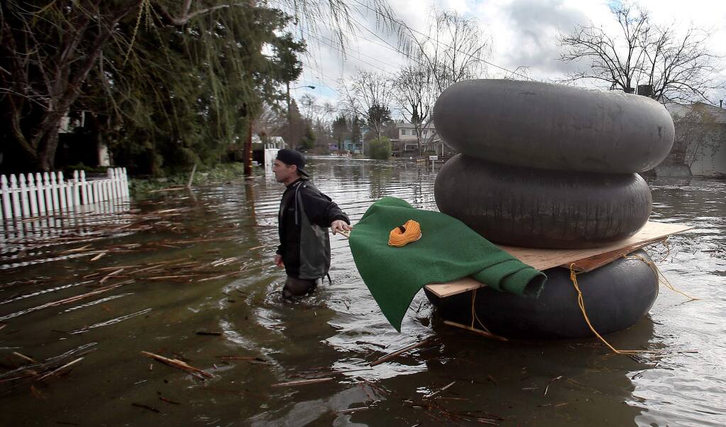James Fipps gathers inner tubes to make a raft on Lakeport's Esplanade Street as Clear Lake continues to inundate homes, Tuesday, Feb. 21, 2017. (KENT PORTER/ PD)