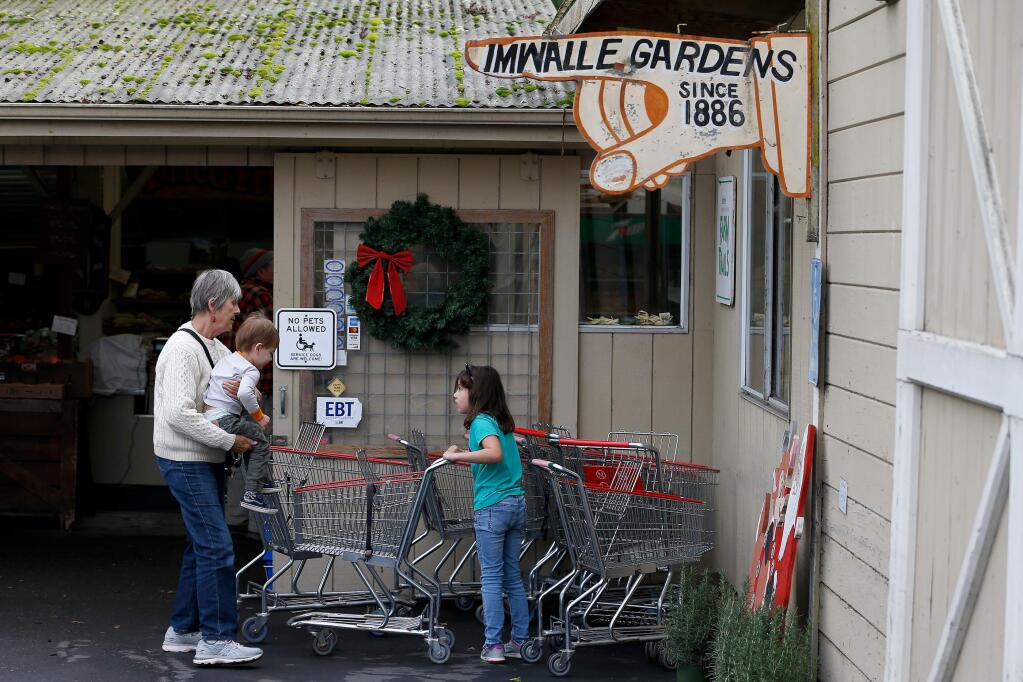 Heather Andrew, left, places her grandson Milo Wiseman, 2, into a cart with help from Milo's older sister Alexandra, 7, as they prepare to shop at Imwalle Gardens in Santa Rosa, California, on Friday, December 20, 2019. (Alvin Jornada / The Press Democrat)