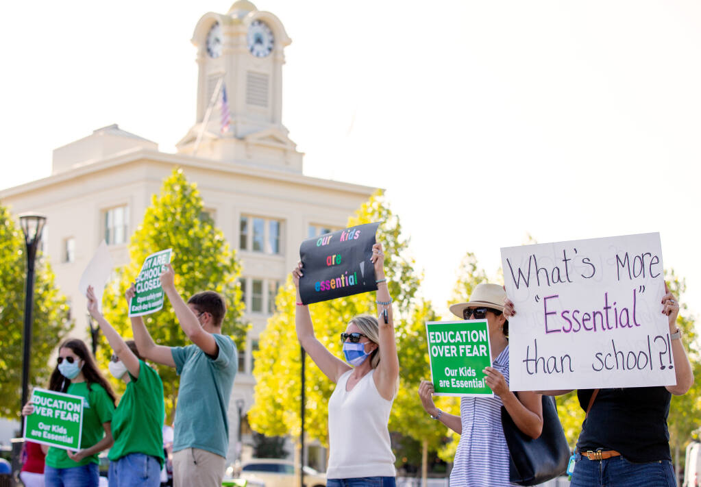 Dozens of parents and their school-age children chant and wave signs during a rally being held to pressure local and state officials to reopen schools amid the COVID-19 pandemic, at Old Courthouse Square in Santa Rosa on Thursday, Sept. 17, 2020. (Alvin A.H. Jornada / The Press Democrat)