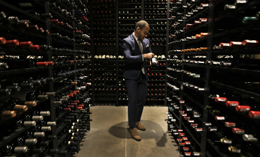 Vincent Morrow, wine director with Press Restaurant in the Napa Valley near St. Helena, Friday, May 4, 2023, makes sure wine labels are turned upright in the Press’s wine cellar. (Kent Porter / The Press Democrat)