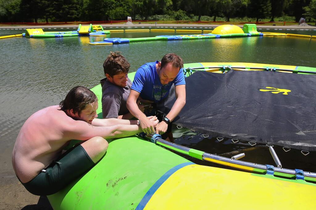Lifeguards Spenser Bushey, left, Jim Boyce and Mitch Kothe work on putting together a trampoline for the new water park in the swim lagoon at Spring Lake Regional Park, in Santa Rosa, on Tuesday, May 24, 2016. The water park will open daily from 11 a.m. to 6 p.m. beginning on Saturday, and will remain open through Labor Day. (Christopher Chung/ The Press Democrat)