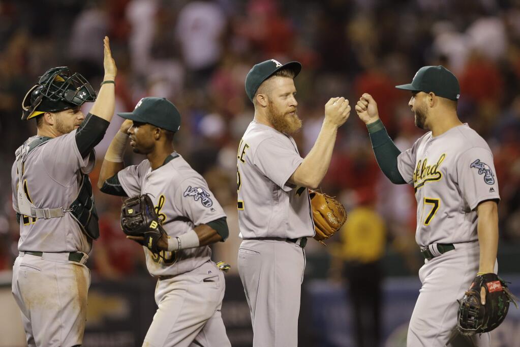 Oakland Athletics relief pitcher Sean Doolittle, second from right, is greeted by teammate first baseman Yonder Alonso, right, after getting the last out to defeat the Los Angeles Angels in a baseball game Thursday, June 23, 2016, in Anaheim, Calif. At left, catcher Stephen Vogt greets right fielder Arismendy Alcantara. The Athletics won, 5-4. (AP Photo/Gregory Bull)