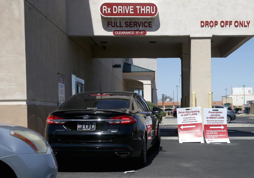 Customers line up at a drive-through self-swab coronavirus test site at a CVS Pharmacy Sunday, June 14, 2020, in Phoenix, Arizona. (AP Photo/Ross D. Franklin)