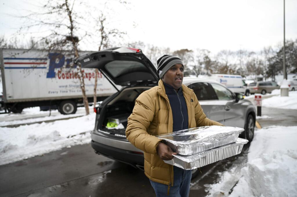Abdirahman Kahin, owner of Afro Deli, donate food to residents of the Cedar Riverside, following a fire on the 14th floor of a public housing high-rise in Minneapolis on Wednesday, Nov. 27, 2019. Several people died and a few people were injured when the fire broke at the building in a heavily immigrant neighborhood of Minneapolis early Wednesday. (Aaron Lavinsky/Star Tribune via AP)