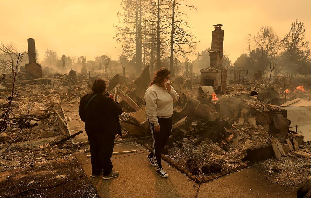Maria Flores and her daughter-in-law Morelia Gaspar look over the ruins of Flores' home in Santa Rosa, Monday Oct. 9, 2017 near Coffey Park. (Kent Porter / Press Democrat) 2017