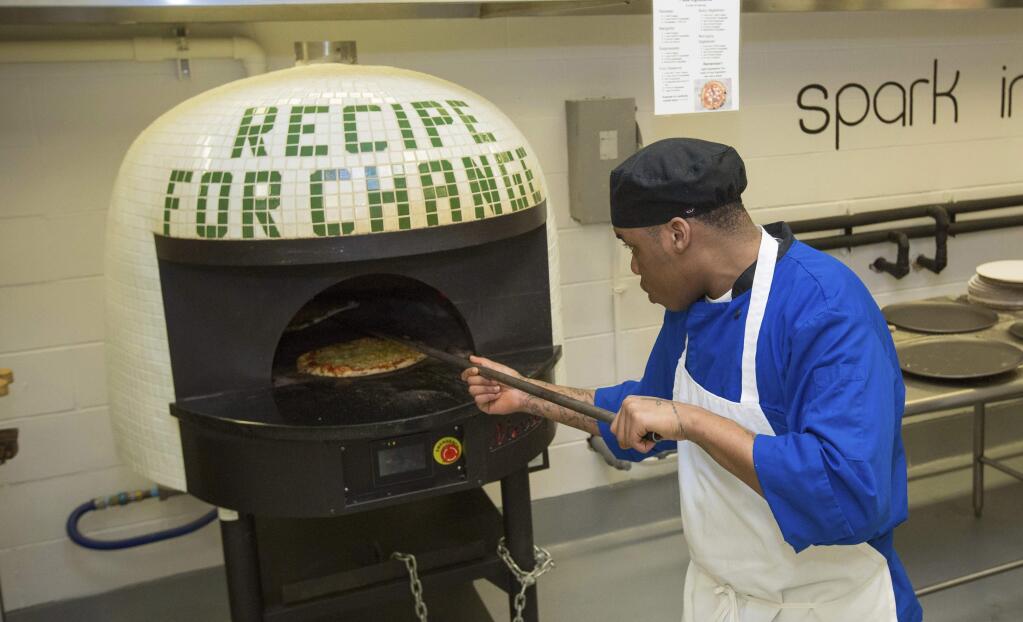 In this May 23, 2017 photo, inmate Marcus Clay, pulls pizza from oven at the Cook County Jail in Chicago. Inmates in the jail's medium-security Division 11 are now allowed to order pizzas made by participants in the jail's 'Recipe for Change' program, which teaches inmates about cooking and nutrition. (AP Photo/Teresa Crawford)