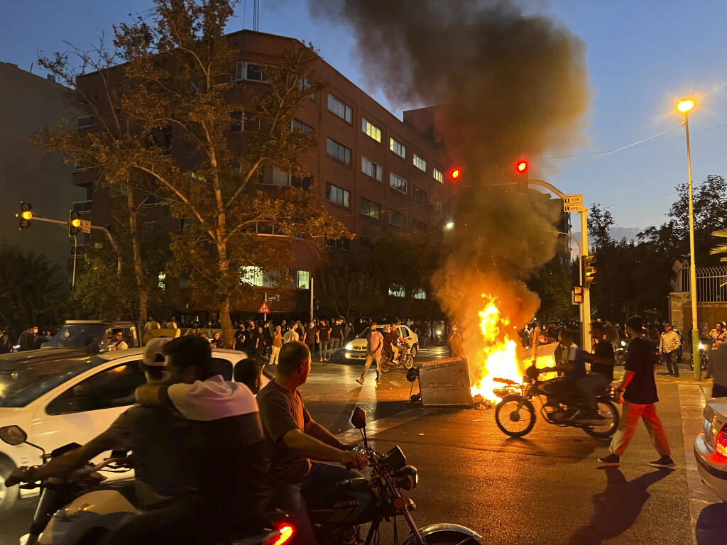 In this Monday, Sept. 19, 2022, photo taken by an individual not employed by the Associated Press and obtained by the AP outside Iran, a police motorcycle and a trash bin are burning during a protest over the death of Mahsa Amini, a 22-year-old woman who had been detained by the nation's morality police, in downtown Tehran, Iran. (AP Photo)
