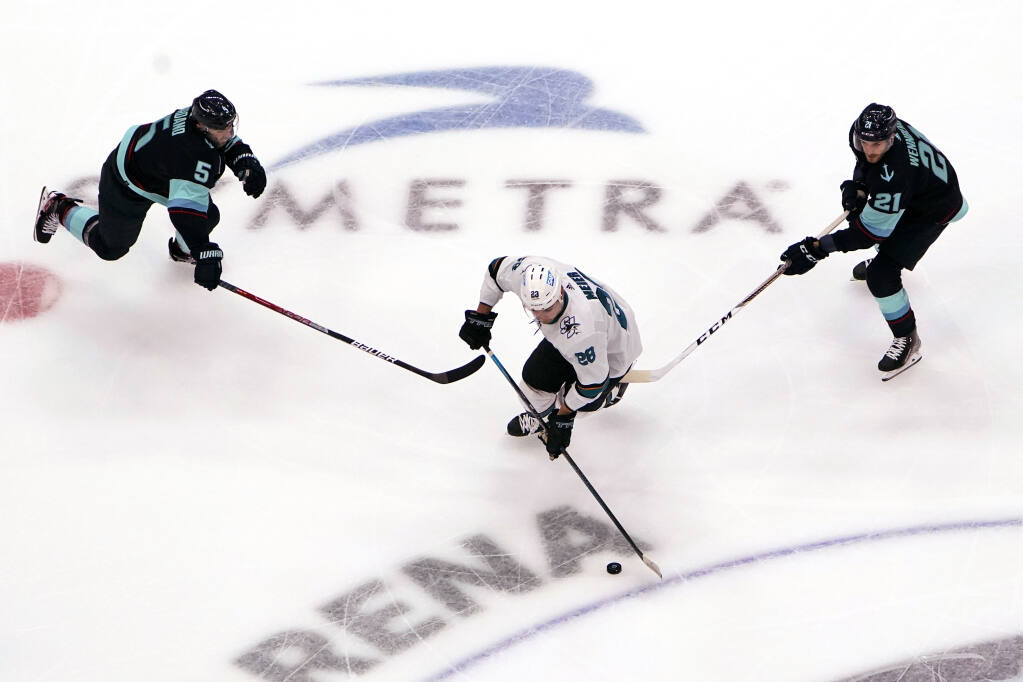 The San Jose Sharks’ Timo Meier skates between the Seattle Kraken’s Mark Giordano and Alex Wennberg in the first period on Thursday, Jan. 20, 2022, in Seattle. (Elaine Thompson / ASSOCIATED PRESS)