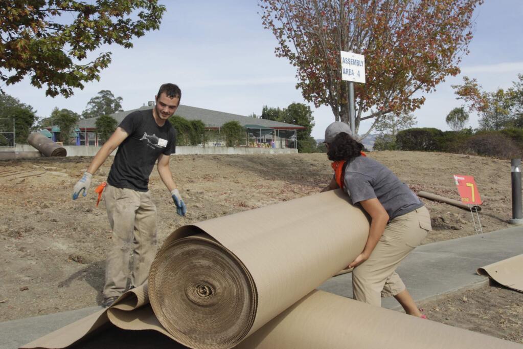 Volunteers Drew Mealor & Natalia Lozoya laying out the cardboard cover at the Mulchstock 2015: the Largest Peaceful Lawn Transformation on Record held on October 24, 2015 in Petaluma's Redwood Business Park. (Jim Johnson/For the Argus-Courier)