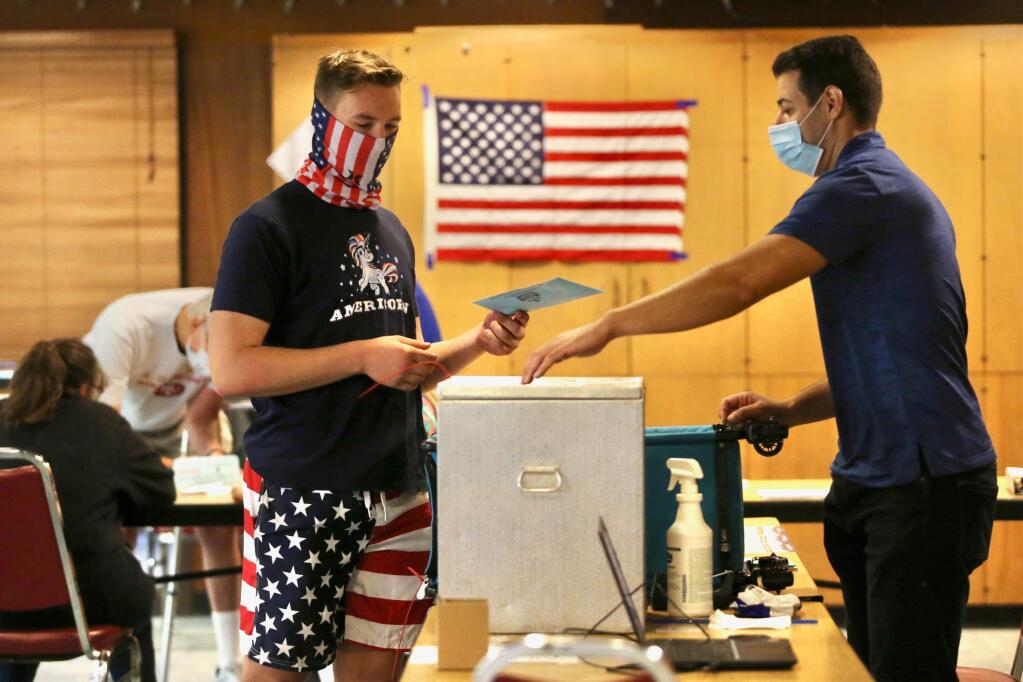 Poll supervisor Alex Hachoud, right, shows Tate Jarrell where to drop his ballot at the Rohnert Park Community Center on Tuesday, Sept. 14, 2021. (Beth Schlanker / The Press Democrat)