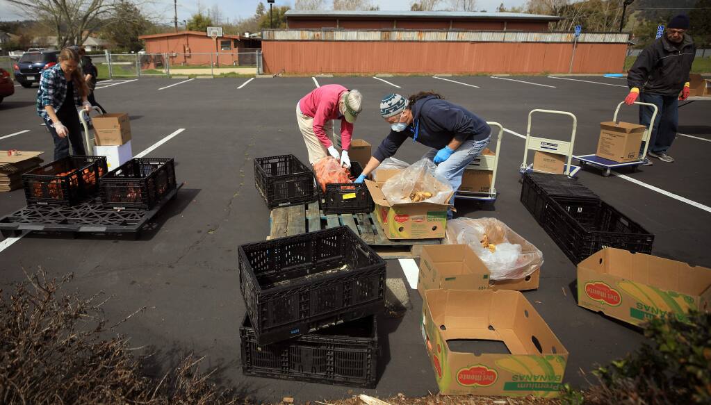Volunteers with the Redwood Empire Food Bank, Friday, March 27, 2020, consolidate the last of the food during a drive through food giveaway in the parking lot of The Lighthouse Church in Rincon Valley. (Kent Porter / The Press Democrat) 2020