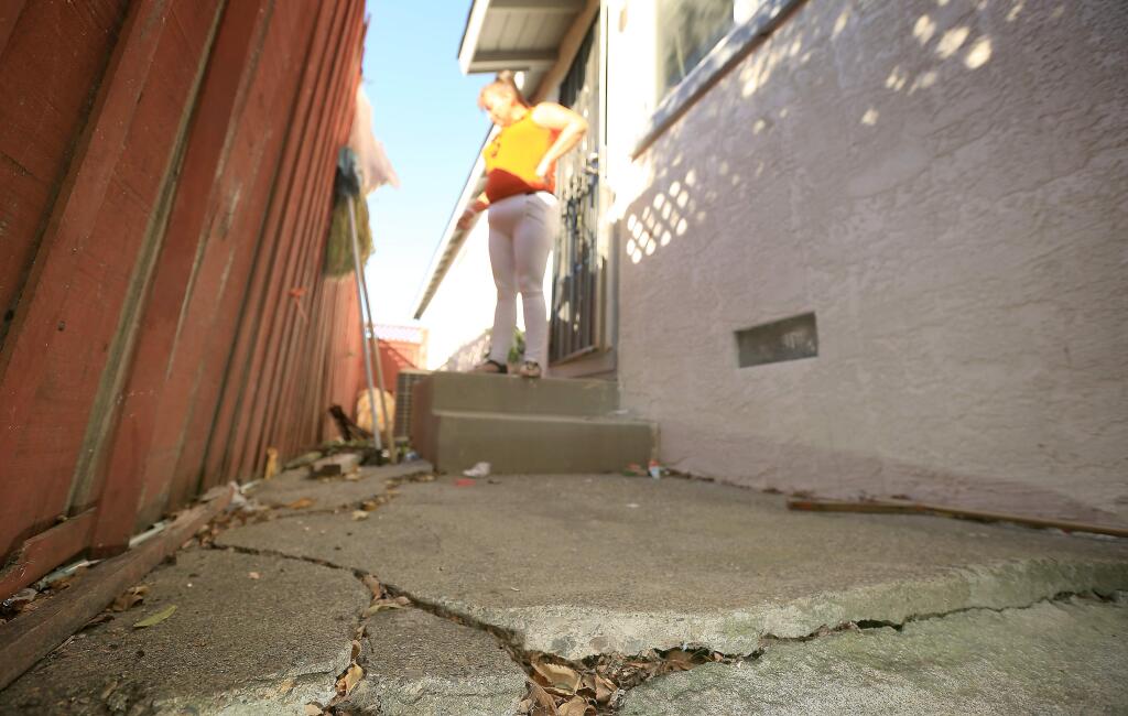 Annabelle Montecino surveys the cracks and lifting to her walkway, damage to a fence and the slight shifting of her foundation, all caused by August's Napa earthquake on Tuesday, Oct. 28, 2014 in American Canyon. (KENT PORTER/ PD)