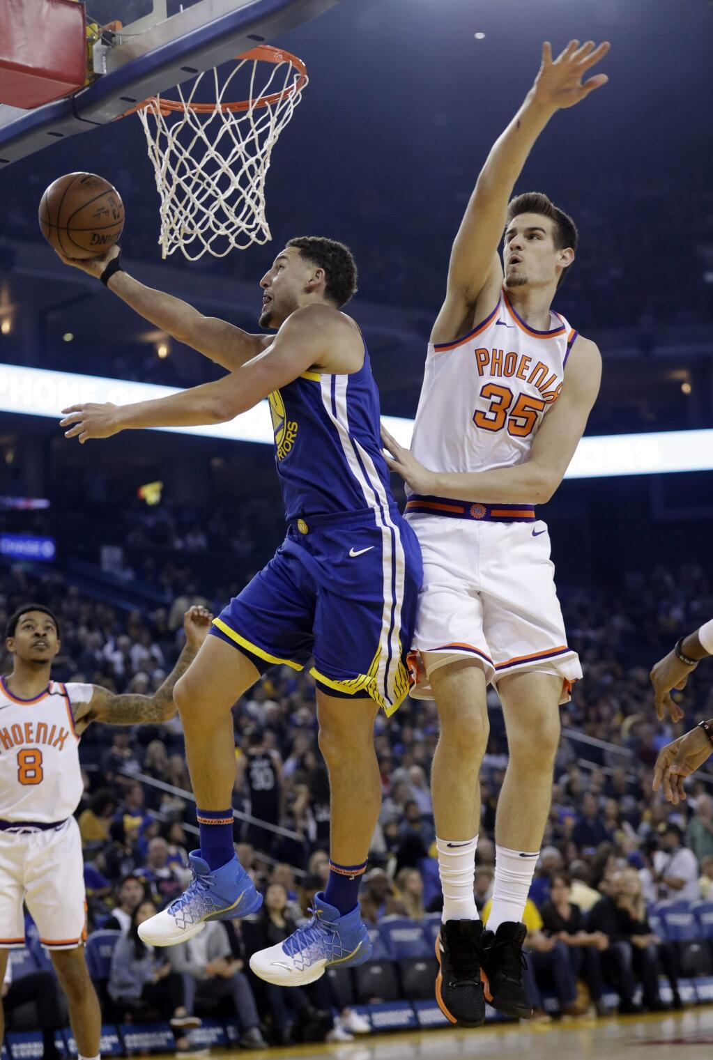 Golden State Warriors' Klay Thompson, left, drives past Phoenix Suns' Dragan Bender (35) during the first half of an NBA basketball game Sunday, April 1, 2018, in Oakland, Calif. (AP Photo/Marcio Jose Sanchez)