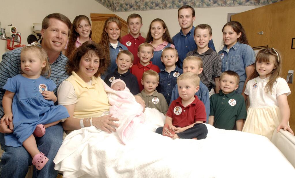 FILE - In this Aug. 2, 2007 file photo, Michelle Duggar, left, is surrounded by her children and husband Jim Bob, second from left, after the birth of her 17th child in Rogers, Ark. TLC is officially cancelling '19 Kids and Counting.' The hit reality show 'will no longer appear on the air,' the network told The Associated Press on Thursday, July 15, 2015. The show had been in limbo since May after revelations that 27-year-old Josh Duggar molested five children including four of his sisters. (AP Photo/ Beth Hall, File)