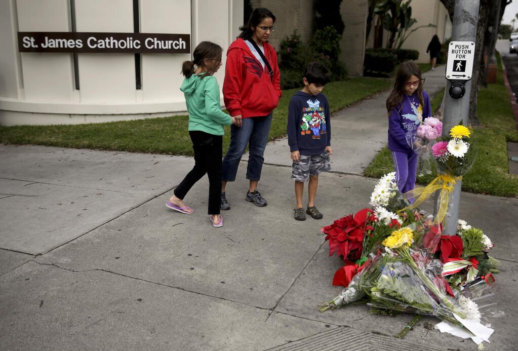 Mourners pay their respects at a make shift memorial Thursday, Dec. 18, 2014 near where a driver suspected of being intoxicated hit a group of pedestrians and another car outside a church as a Christmas service ended Wednesday night in Redondo Beach, Calif. (AP Photo/Chris Carlson)