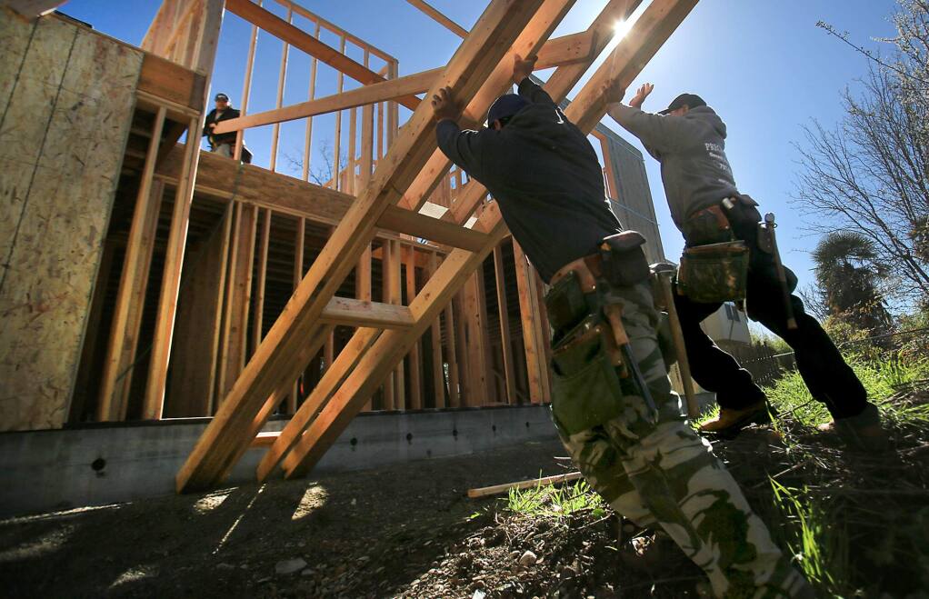 Miguel Gonzalez, left and Raul Rivas combine efforts to lift the framing of an exterior wall as Raul Magana, top left, pulls the structure towards the house, Wednesday March 1, 2017 as the three build a granny unit in Santa Rosa. (Kent Porter / The Press Democrat) 2017