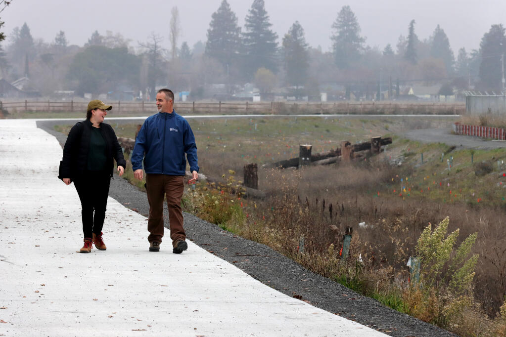 Lauren Alpert, Sonoma County Agricultural Preservation and Open Space District communications specialist, and Steve Brady, City of Santa Rosa senior environmental specialist, walk along a newly renovated walkway next to Colgan Creek, part of an area completed in an earlier phase of the project, Thursday, Dec. 22, 2022, in Santa Rosa. (Darryl Bush/For The Press Democrat)