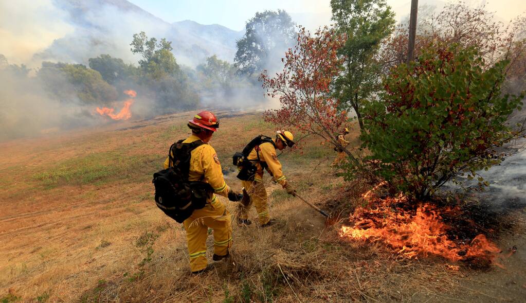 Cal Fire firefighters jump on a hot spot off Highway 20 in Lake County just east of Blue Lakes in 2014. (KENT PORTER/ PD FILE)