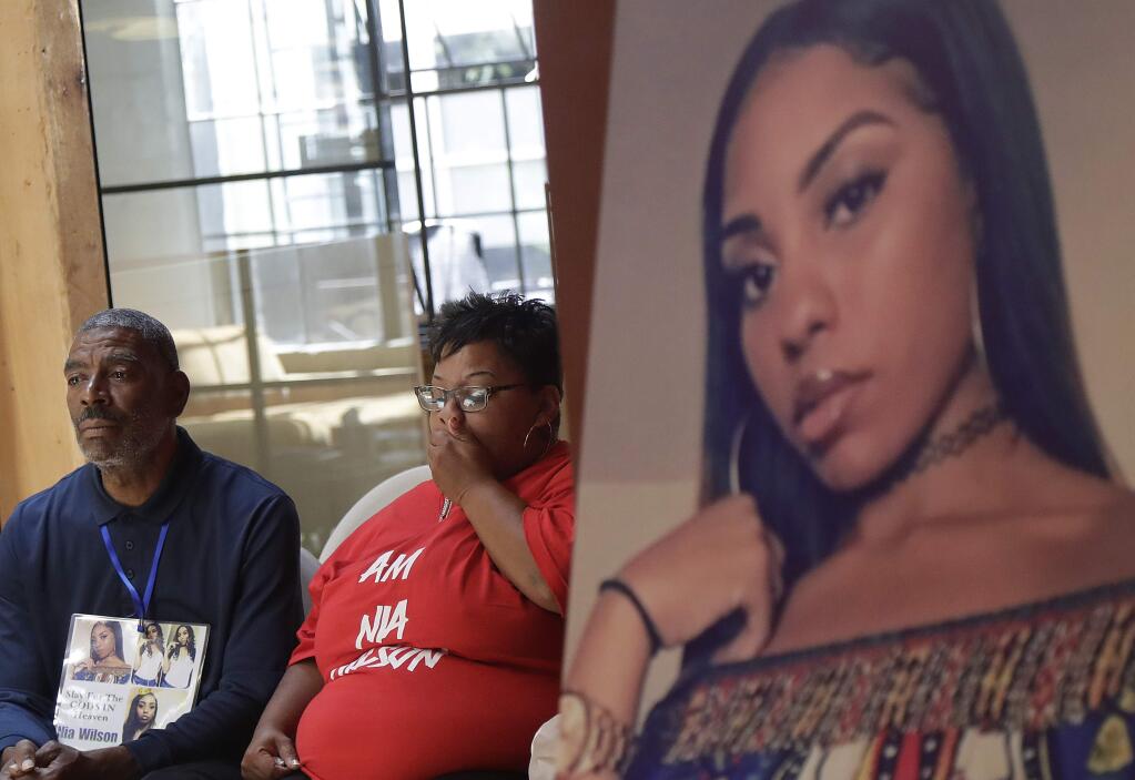 FILE - In this Aug. 17, 2018, file photo, a photo of victim Nia Wilson, right, is displayed at a news conference as her father Ansar El Muhammad, left, and her mother, Alicia Grayson, listen in San Francisco. An Alameda County jury found 29-year-old John Lee Cowell guilty of murdering Nia Wilson at the MacArthur BART station in Oakland as she was returning home from a family gathering with her two sisters. Jurors also found Cowell guilty of attempted murder in the stabbing of Wilson's sister, who survived severe injuries to her neck. Wilson's stabbing death in July 2018 horrified bystanders and added to BART's reputation as unsafe. (AP Photo/Jeff Chiu, File)
