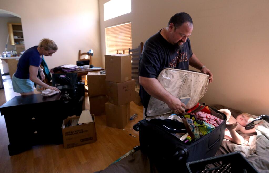 Chris Keys, center and his wife Sara Jakel-Keys, left, pack up their home in preparation for a move to a new home they just purchased while their son Isaac Keys, 2, right, plays on the bed, Thursday, April 30, 2015. (CRISTA JEREMIASON / The Press Democrat)
