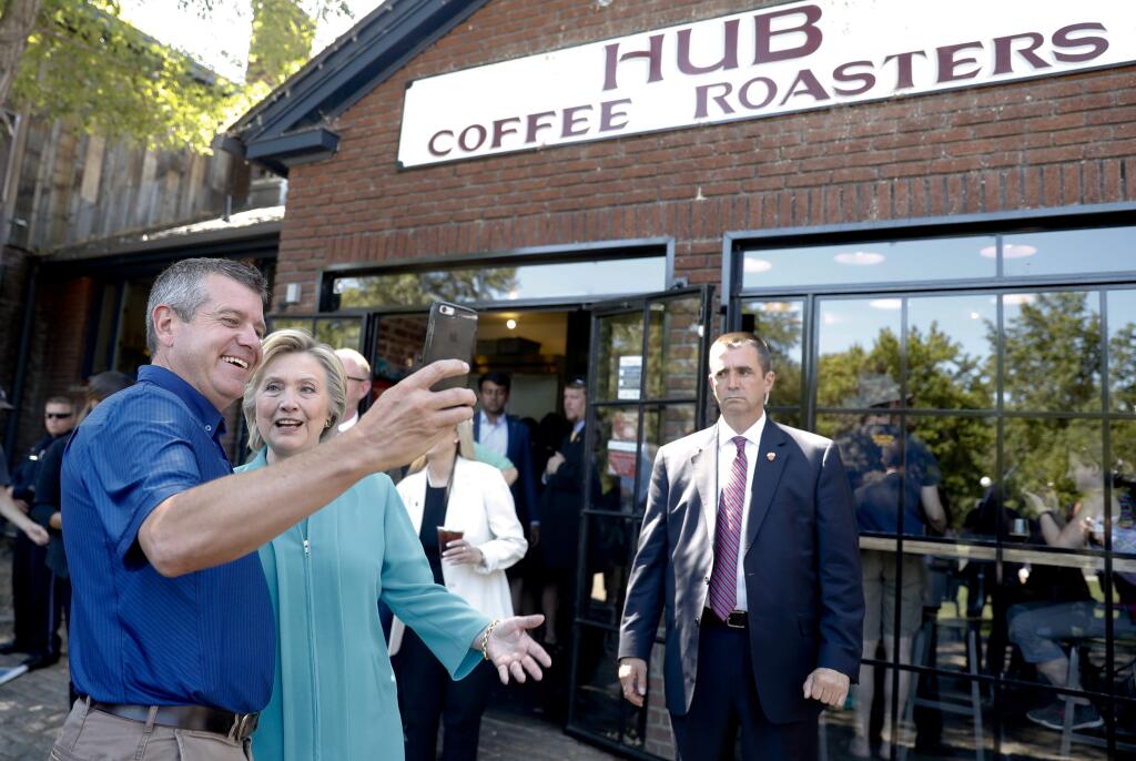 Democratic presidential candidate Hillary Clinton takes photos with patrons outside Hub Coffee Roasters in Reno, Nev., Thursday, Aug. 25, 2016. (AP Photo/Carolyn Kaster)