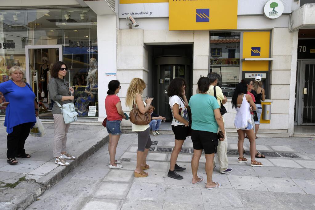 People line up at an ATM outside a Piraeus bank branch in Athens, Monday, June 29, 2015. Anxious Greeks lined up at ATMs as they gradually began dispensing cash again on the first day of capital controls imposed in a dramatic twist in Greeces five-year financial saga. Banks will remain shut until next Monday, and a daily limit of 60 euros ($67) has been placed on cash withdrawals from ATMs. (AP Photo/Thanassis Stavrakis)