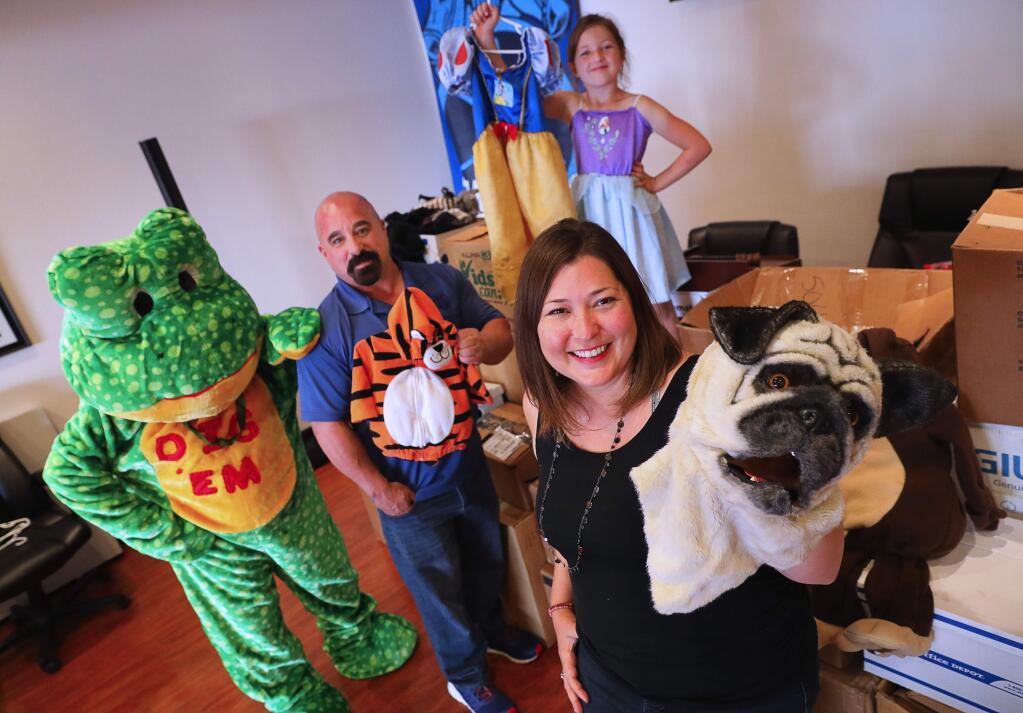 Julie Etchell Battles, right, with the help of Michael Yates, president of Teamsters Local Union 665, organized a Halloween costume drive for kids following the North Bay fires last year. With 400 costumes left over from last year, they are collecting costumes even more costumes for survivors again this year, and plan to distribute costumes for survivors of this year's Mendocino County and Redding fires. In the background, Alexandria Battles, 5, helps to model some costumes.(Christopher Chung/ The Press Democrat)