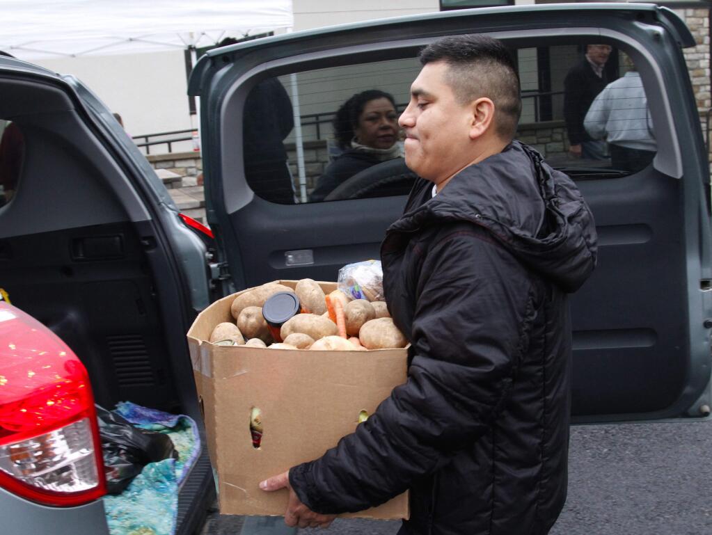 Bill Hoban/Index-TribuneFeeding the needyMiguel Santiago hoists a box of food into a vehicle Saturday at the annual FISH holiday food basket program. FISH distributed 360 food boxes at the giveaway that was held at Hanna Boys Center. The food for the baskets came from numerous local organizations including Sonoma Valley Public Schools that collect donations in food barrels, Sonoma Valley Cub and Boy Scouts and Sonoma Raceway get the program launched every year by collecting donations. This year, 75 volunteers helped somewhere along the way, whether it was moving food, sorting food or helping to distribute it.