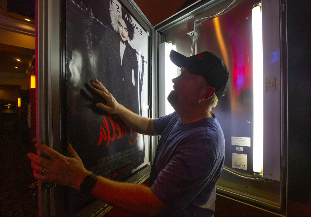 Preparing for the 2021 re-opening, Brian Young, proprietor of Prime Cinemas, installed a movie poster on Tuesday, May 25, 2021. (Photo by Robbi Pengelly/Index-Tribune)