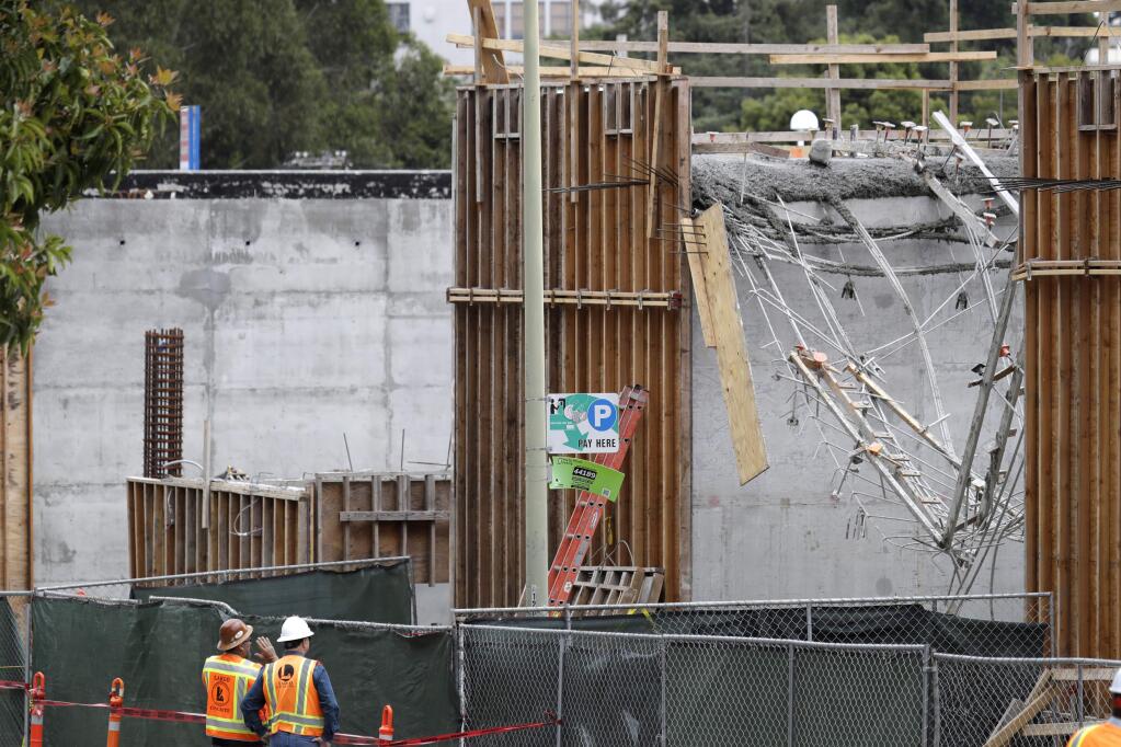 Workers inspect the scene of an accident at a construction site Friday, May 26, 2017, in Oakland, Calif. Officials say scaffolding and wet concrete apparently gave way at a building site in the San Francisco Bay Area, injuring over a dozen workers. (AP Photo/Marcio Jose Sanchez)