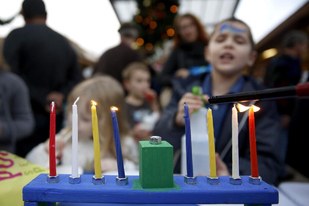 A menorah is lit during a Hanukkah celebration at Montgomery Village on Sunday, December 21, 2014 in Santa Rosa, California . (BETH SCHLANKER/ The Press Democrat)