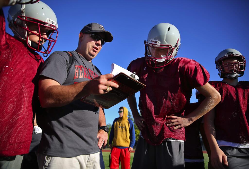 Healdsburg football head coach Todd Beth goes over a play with quarterback Levi Yeley during practice, in Healdsburg, on Thursday, August 13, 2015. (Christopher Chung/ The Press Democrat)