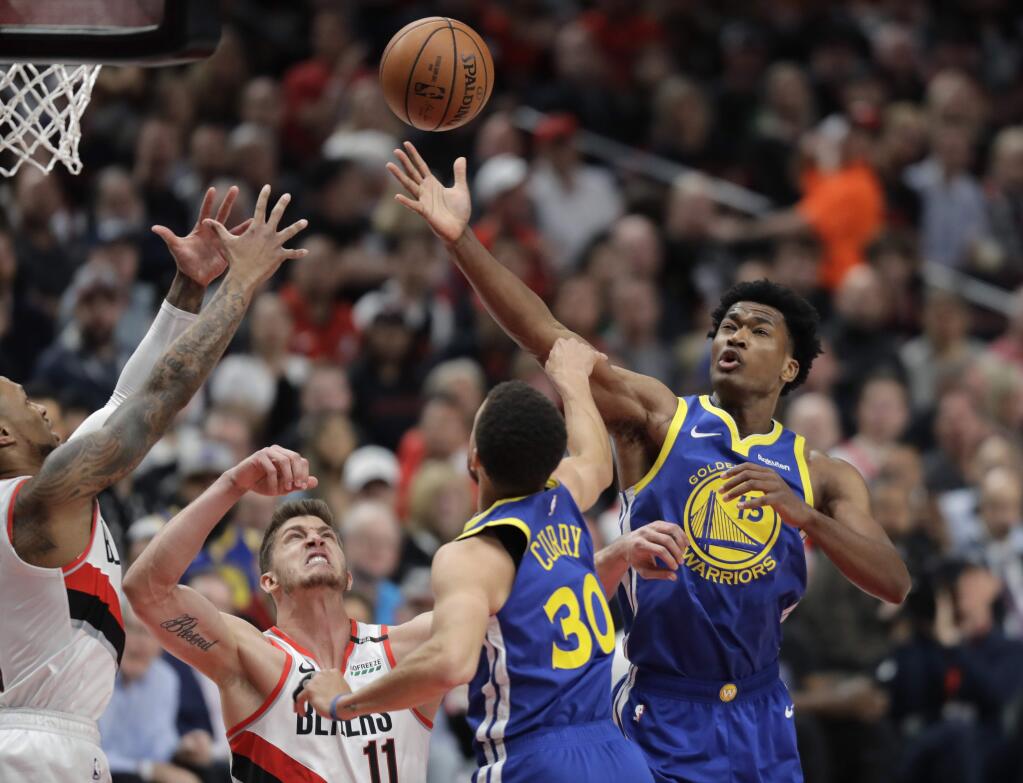 The Golden State Warriors center Damian Jones, right, reaches for a rebound above the Warriors' Stephen Curry and Portland Trail Blazers forward Meyers Leonard during the first half of Game 3 of the NBA Western Conference finals Saturday, May 18, 2019, in Portland, Ore. (AP Photo/Ted S. Warren)