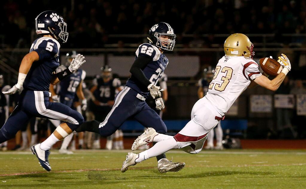 Cardinal Newman's Kyle Carinalli (23), right, makes a leaping catch for a first down ahead of Marin Catholic's Jake Gammon (22) and Gaven Cooke (5) during the first half of the NCS Division 3 varsity football championship game between Cardinal Newman and Marin Catholic high schools in Rohnert Park, California on Saturday, December 2, 2017. (Alvin Jornada / The Press Democrat)