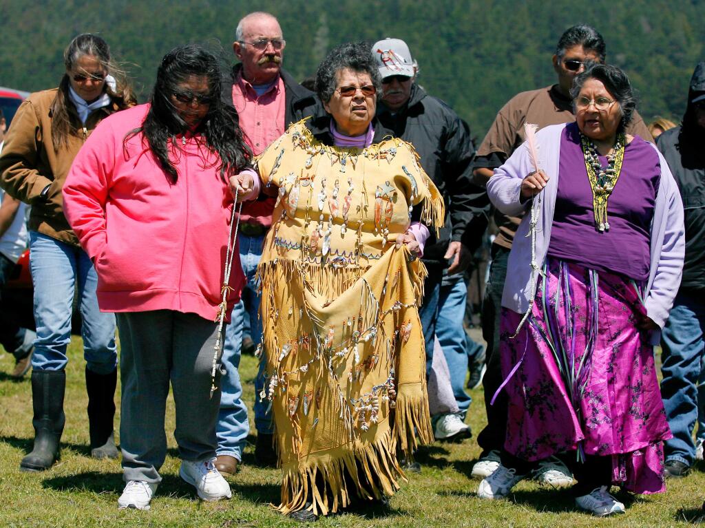 The Stewarts Point Kashia Band of Pomo's Violet Parrish Chappell, center, helped by sisters Vana Parrish Lawson, left and Vivian Parrish Wilder, right, to the cliff where a ceremonial rock was thrown in the ocean on the Arch Richardson ranch, during a Native American blessing as fishing grounds close. Richardson, third from left, and his family have allowed the Kashia Pomo tribe to cross his land to fish for abalone, sea weed and fish as well as collecting shells for jewelry. The state's new marine preserve system will prevent the tribe from fishing.