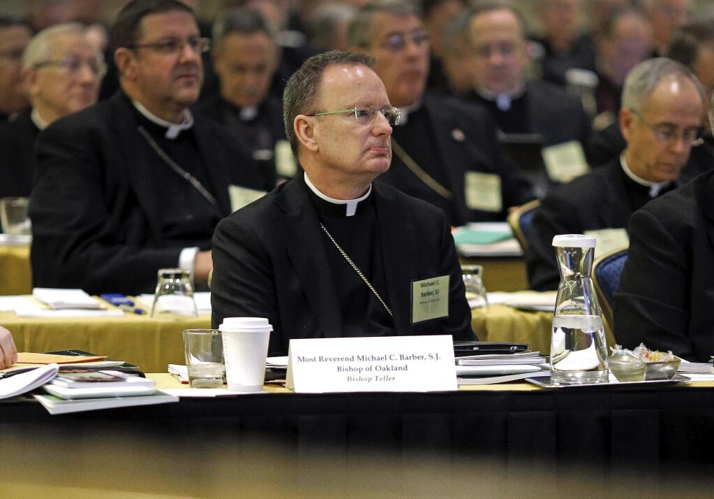 FILE - In this Nov. 12, 2013, file photo, Roman Catholic Diocese of Oakland Bishop Michael Barber, center, listens to a presentation alongside fellow bishops at the United States Conference of Catholic Bishops' annual fall meeting in Baltimore. The Catholic Diocese of Oakland, Calif., has released the names of 45 priests, deacons and religious brothers who officials say are 'credibly accused' of sexually abusing minors. The San Francisco Chronicle says Monday that Oakland's list goes back to 1962, when the diocese was founded. None of the men are currently in the ministry. Of the 45 people named, 20 were priests. (AP Photo/Patrick Semansky, File)