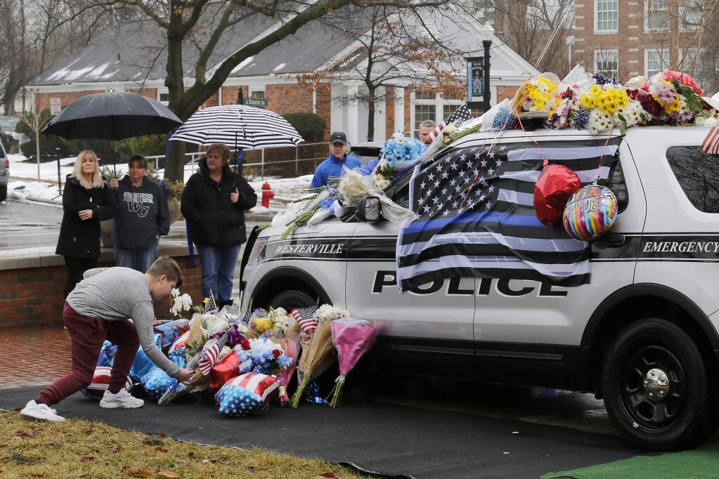 Mourners gather and leave flowers on a police cruiser parked in front of City Hall in Westerville, Ohio, where police Officers Anthony Morelli and Eric Joering were killed Saturday when they came under fire while responding to a domestic violence call. (SAM GREENE / Cincinnati Enquirer)
