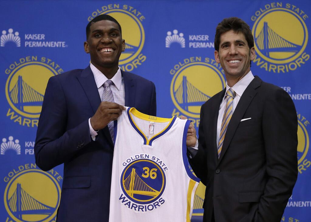 Golden State Warriors' Kevon Looney, left, holds his new jersey beside general manager Bob Myers during an NBA basketball conference, Friday, June 26, 2015, in Oakland, Calif. Looney a forward from UCLA, was selected 30th overall in the first round of Thursday's NBA draft. (AP Photo/Ben Margot)