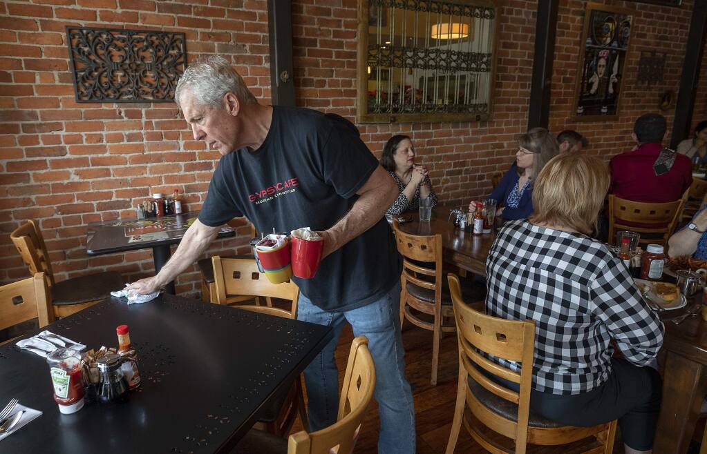 Rob Scheid wipes down a table on a crowded Friday morning at the Gypsy Cafe in Sebastopol. (photo by John Burgess/The Press Democrat)