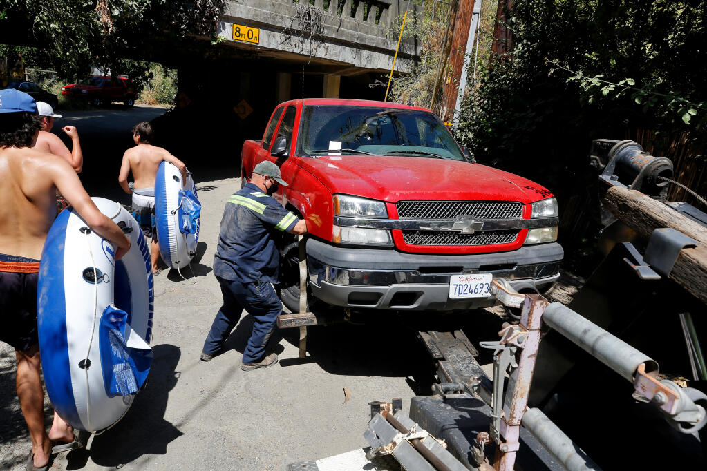 Tow truck driver Dave Myers, right, of Cream's Towing prepares to tow away a pickup truck that was illegally parked and cited by California Highway Patrol officers on River Drive near the Mother's Beach access in Forestville on Saturday, Aug. 15, 2020. (Alvin A.H. Jornada / The Press Democrat)