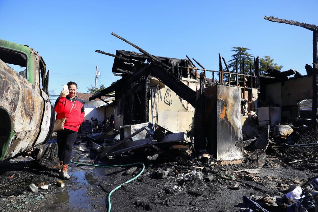 Gabriella Marquez walks among the burned remains of the home that she was living in with her family, along West College Avenue, in Santa Rosa, on Wednesday, March 28, 2018. (Christopher Chung/ The Press Democrat)
