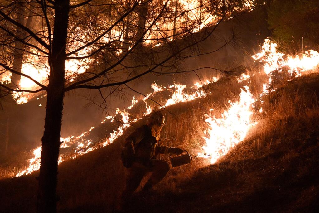 A Cal Fire firefighter ignites a backing fire on a hillside along Highway 20 during the fifth day of the Rocky Fire near Clearlake Oakson Sunday, August 2, 2015. (Alvin Jornada for The Press Democrat)
