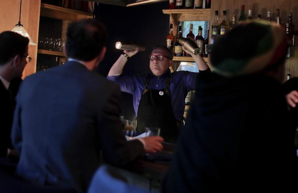 Coup co-founder Sother Teague mixes drinks for customers shortly after opening the bar, Tuesday, April 25, 2017, in New York. As a response to the Trump Administration, the bar in Manhattan's East Village offers patrons the chance to put their money where their politics are by earmarking where the profits should go from a range of liberal or progressive options like the American Civil Liberties Union or Planned Parenthood. (AP Photo/Julie Jacobson)