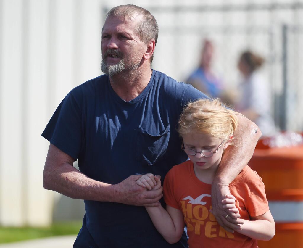 Joey Taylor walks with his daughter Josie Taylor after picking her up at Oakdale Baptist Church on Wednesday, Sept. 28, 2016, in Townville, S.C. Students were evacuated to the church following a shooting at Townville Elementary School. A teenager opened fire at the South Carolina elementary school Wednesday. (AP Photo/Rainier Ehrhardt)