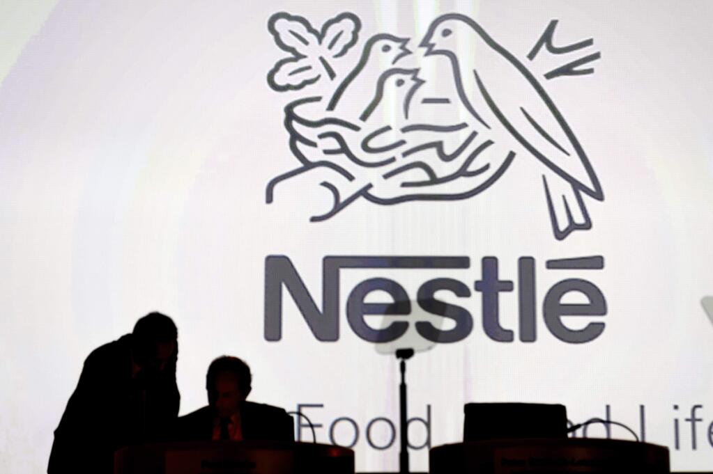 FILE - In this April 7, 2016, file photo Nestle's directors speak in front of the Nestle's logo during the general meeting of Nestle Group, in Lausanne, Switzerland. Nestle has entered an agreement to bring Starbucks products to millions of homes worldwide, announced Monday, May 7, 2018. (Laurent Gillieron/Keystone via AP, File)