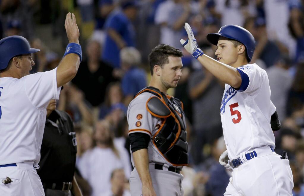 Los Angeles Dodgers' Corey Seager, right, celebrates his two-run home home with A.J. Ellis, left, as San Francisco Giants catcher Buster Posey stands nearby during the eighth inning of a baseball game in Los Angeles, Saturday, April 16, 2016. (AP Photo/Chris Carlson)