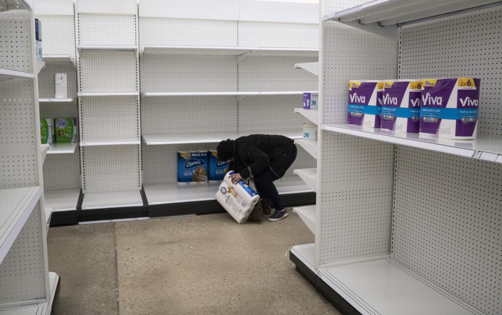 Deanna Butts reaches for one of the last packages of toilet paper at Target in the Tenleytown area of Washington, Tuesday, March 17, 2020. Supplies are restocked as trucks come in but the coronavirus outbreak is causing a current shortage of some items. (AP Photo/Carolyn Kaster)