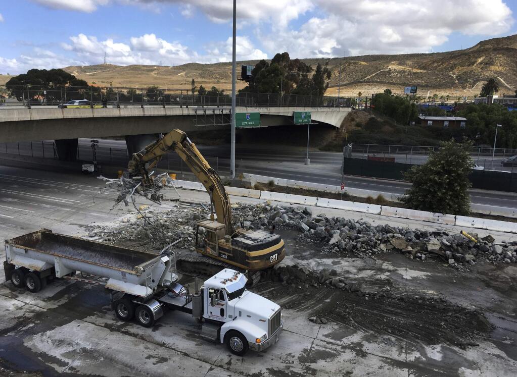 FILE - In this Saturday, Sept. 23, 2017, file photo, heavy machinery and construction crews works on California's Interstate 5 on the first day of a 57-hour closure of all Mexico-bound car traffic at the San Ysidro border crossing in San Diego, Calif. U.S. officials reopened the freeway lanes to Tijuana, Mexico early Monday, Sept. 25, at the U.S. border crossing ahead of schedule after a weekend shutdown for work on a $741 million expansion project. California Department of Transportation spokeswoman Caridad Sanchez said traffic began flowing again just after midnight. It connects San Diego to Tijuana. (AP Photo/Elliot Spagat, File)