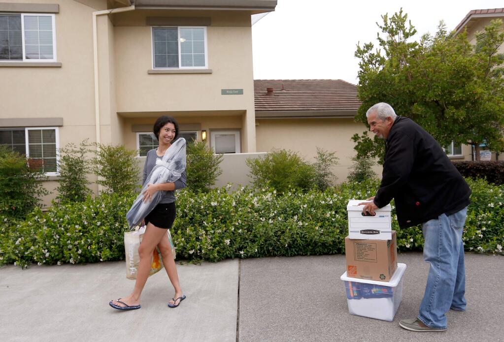 Sophomore communications major Ava Garcia of Concord glances back toward her father Rubel Garcia who pauses for a breather while carrying a stack of heavy boxes the long distance from the parking lot to Ava's dorm room at Sonoma State University in Rohnert Park, California, on Sunday, August 20, 2017. (Alvin Jornada / The Press Democrat)