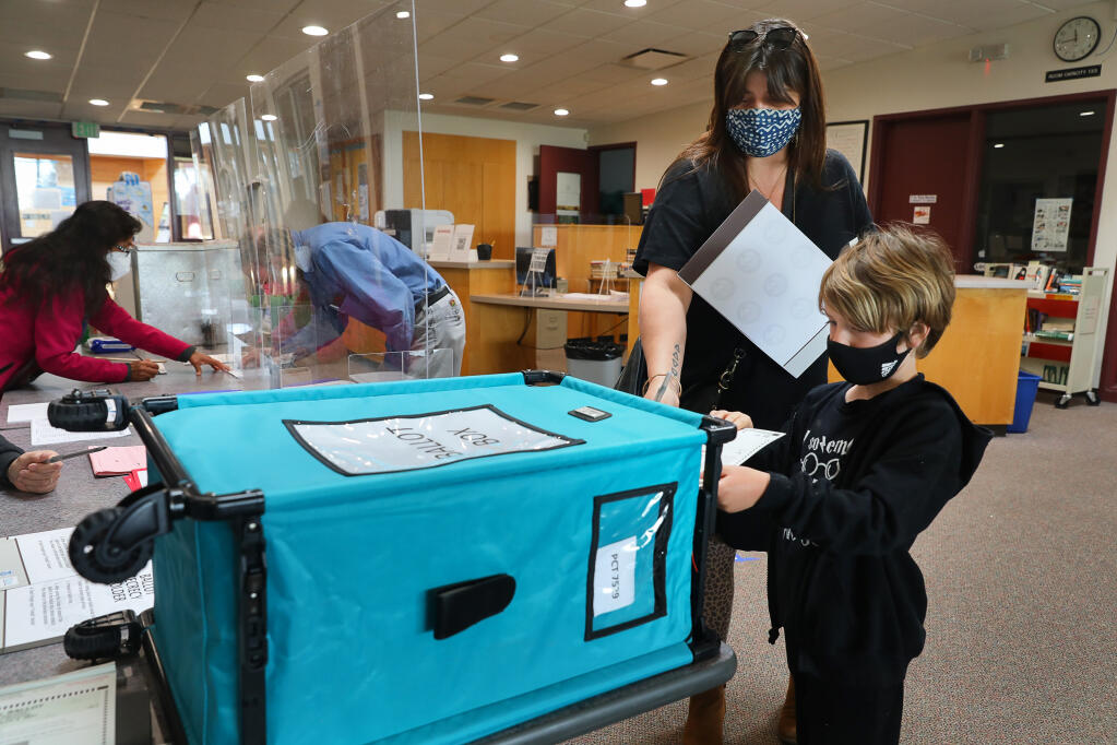 Amy Palmer and her son, Reed, drop her ballot into the ballot box at the El Molino High School library polling location in Forestville on Tuesday, March 2, 2021.   (Christopher Chung/ The Press Democrat)